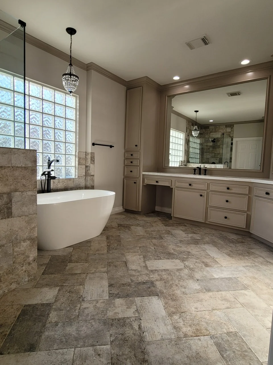 Spacious bathroom renovation with freestanding tub, custom vanity and stone-look floor tile