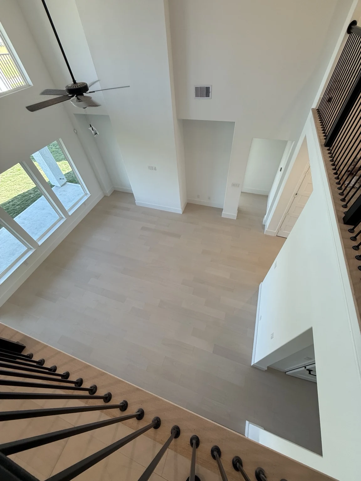 Large empty room viewed from above with light engineered hardwood flooring