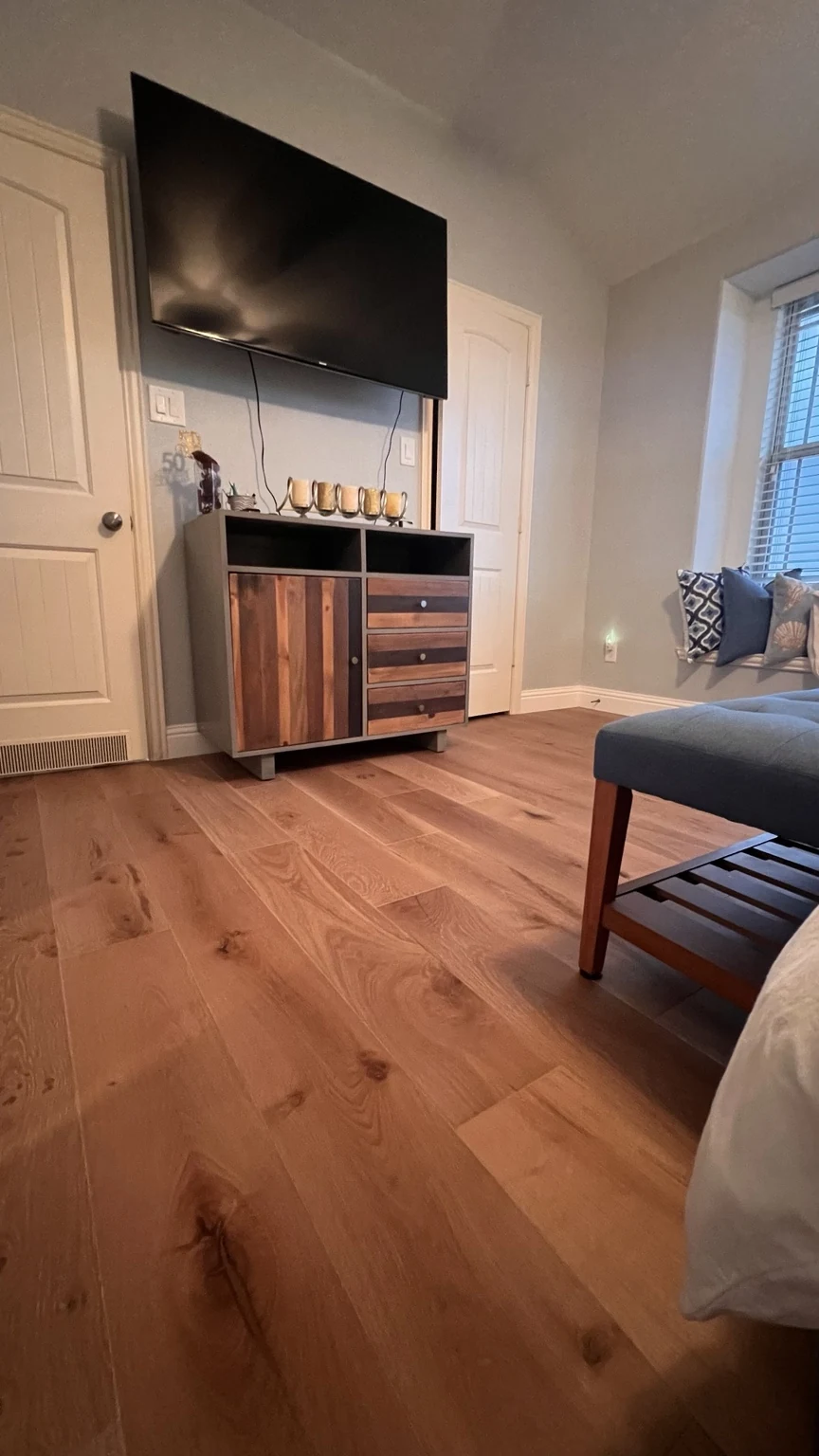 Warm oak engineered hardwood flooring in a bedroom with wood accent cabinetry