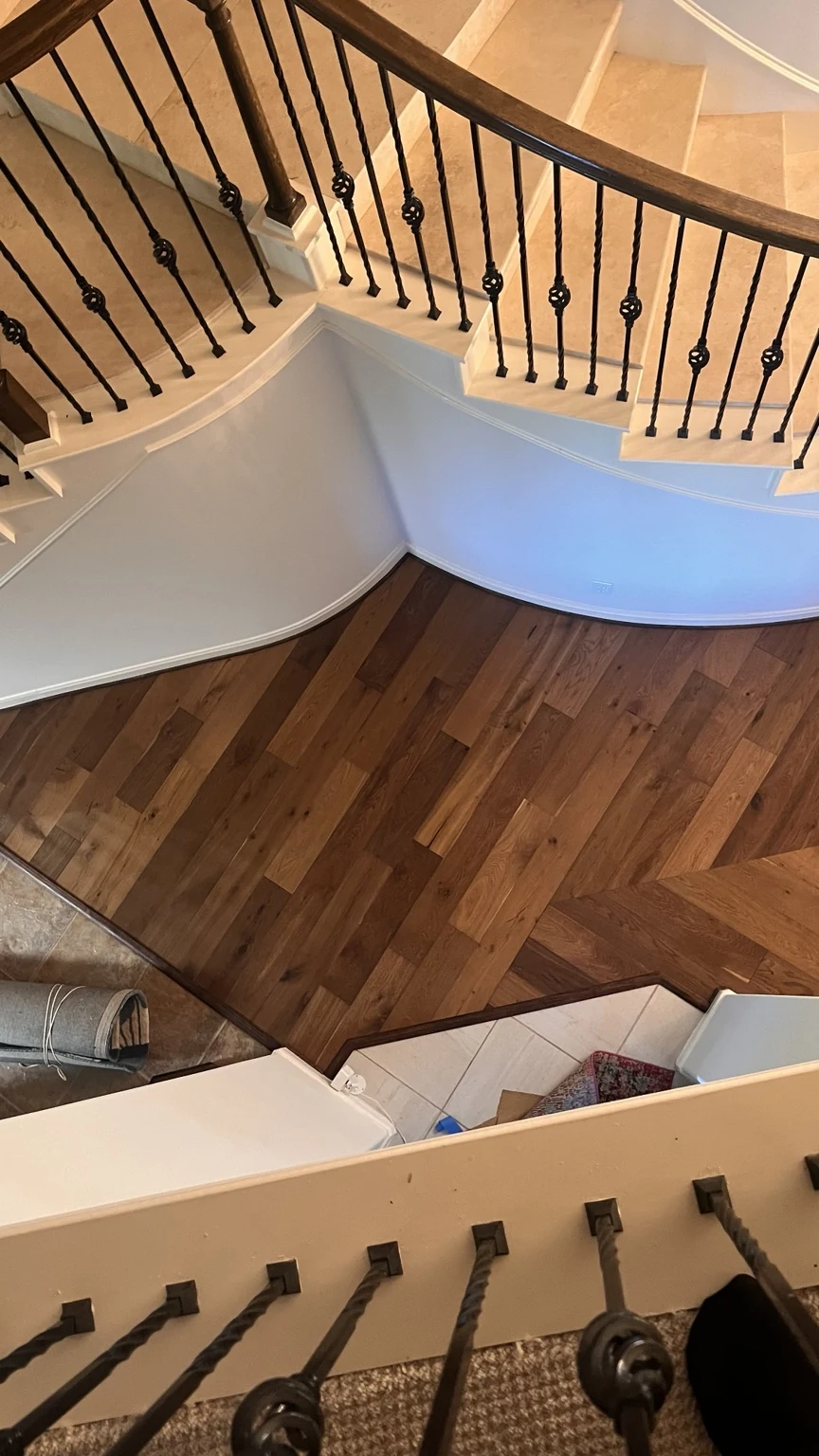 Hardwood flooring viewed from above beside a curved staircase