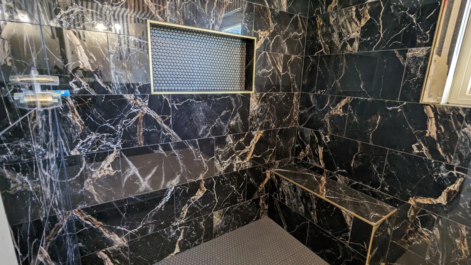 Dark marble-look tile shower wall with recessed niche