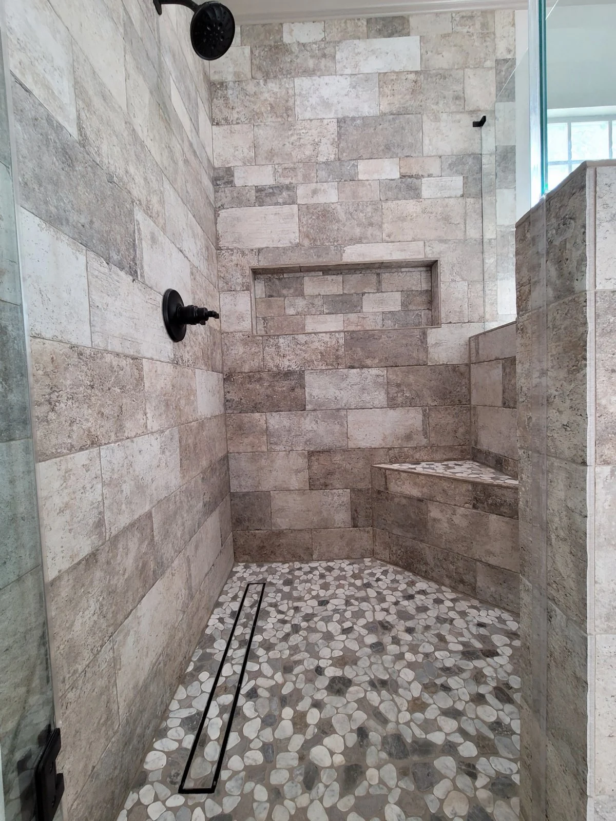 Custom stone-look shower tile and pebble mosaic shower floor