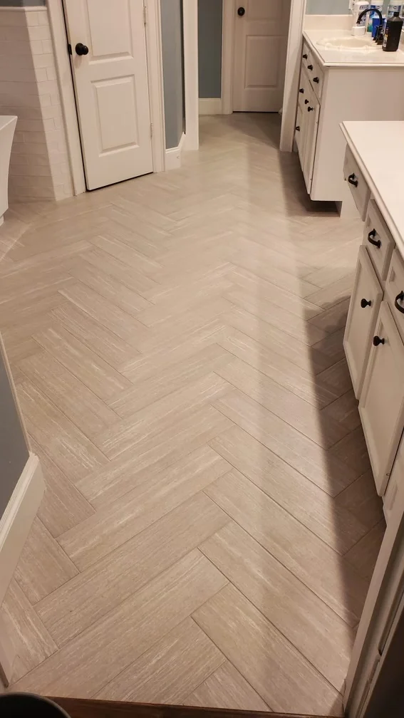 Light herringbone tile floor beside bathroom vanity