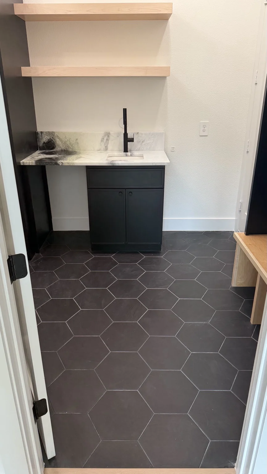 Laundry room with dark hexagonal floor tile